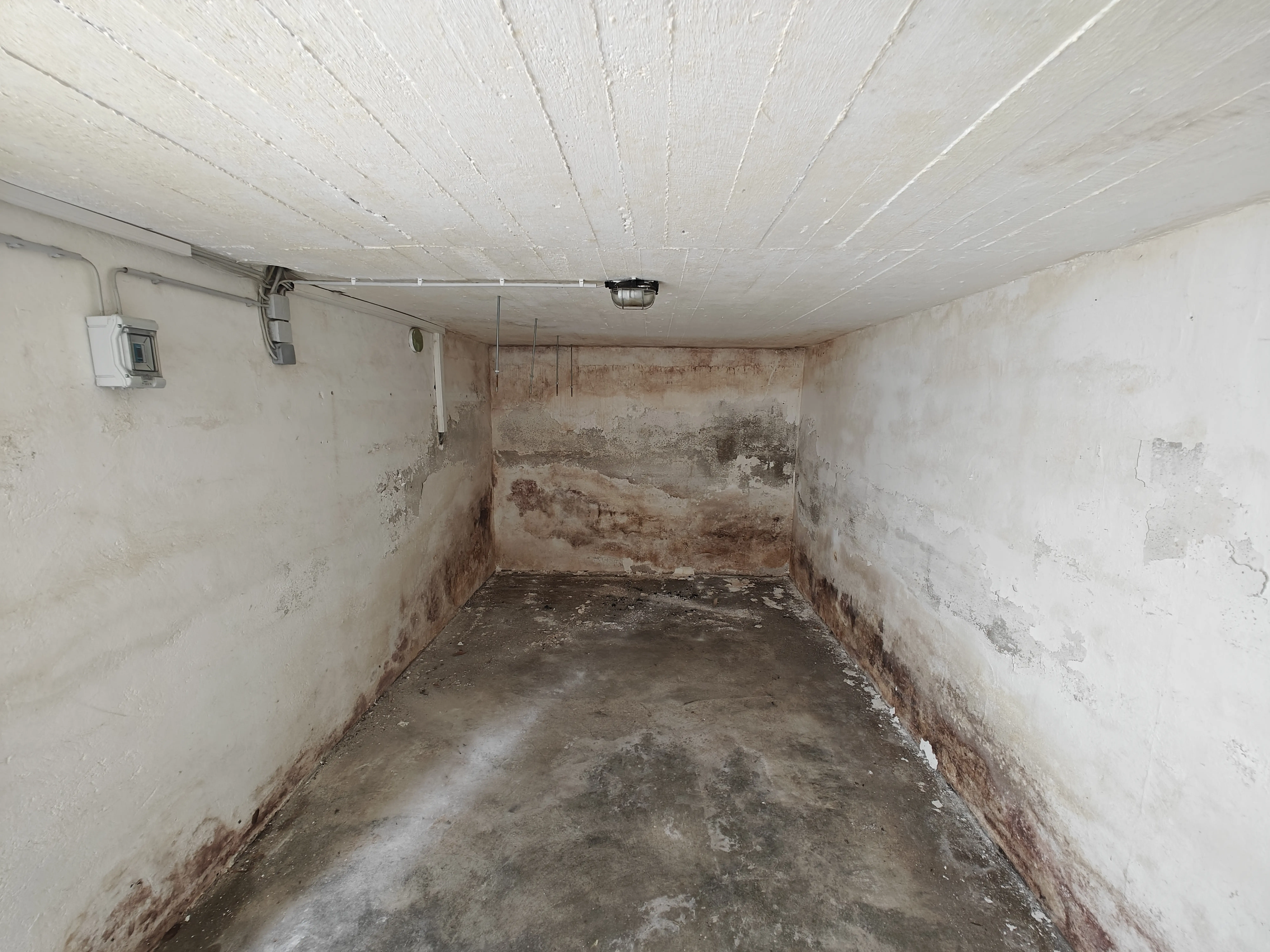 Erdberührter Kellerraum unter einer Garage vor Beginn der Innenabdichtung mit feuchten, beschädigten Wänden